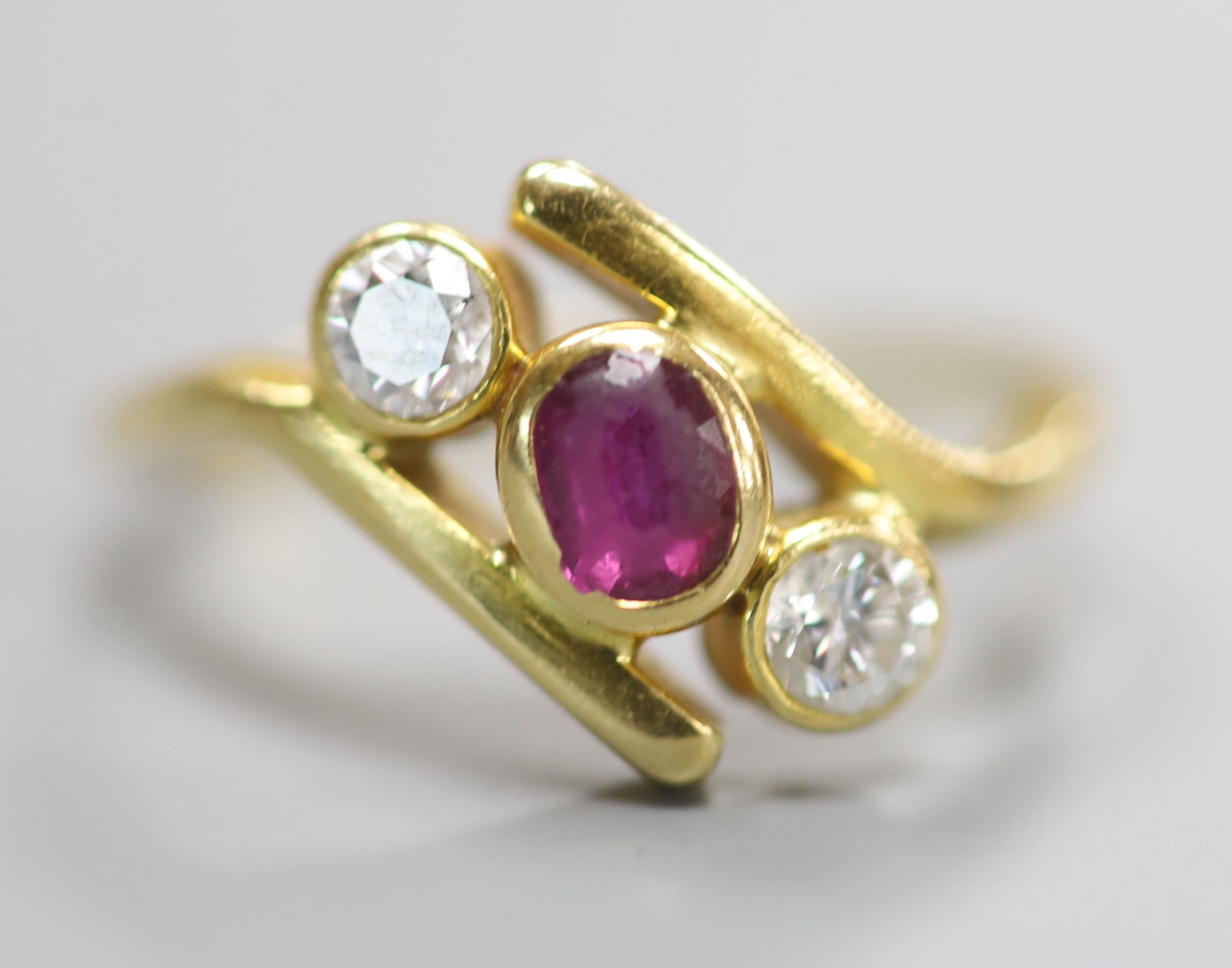 A 750 yellow metal, ruby and diamond three stone crossover ring, size P, gross 4 grams.